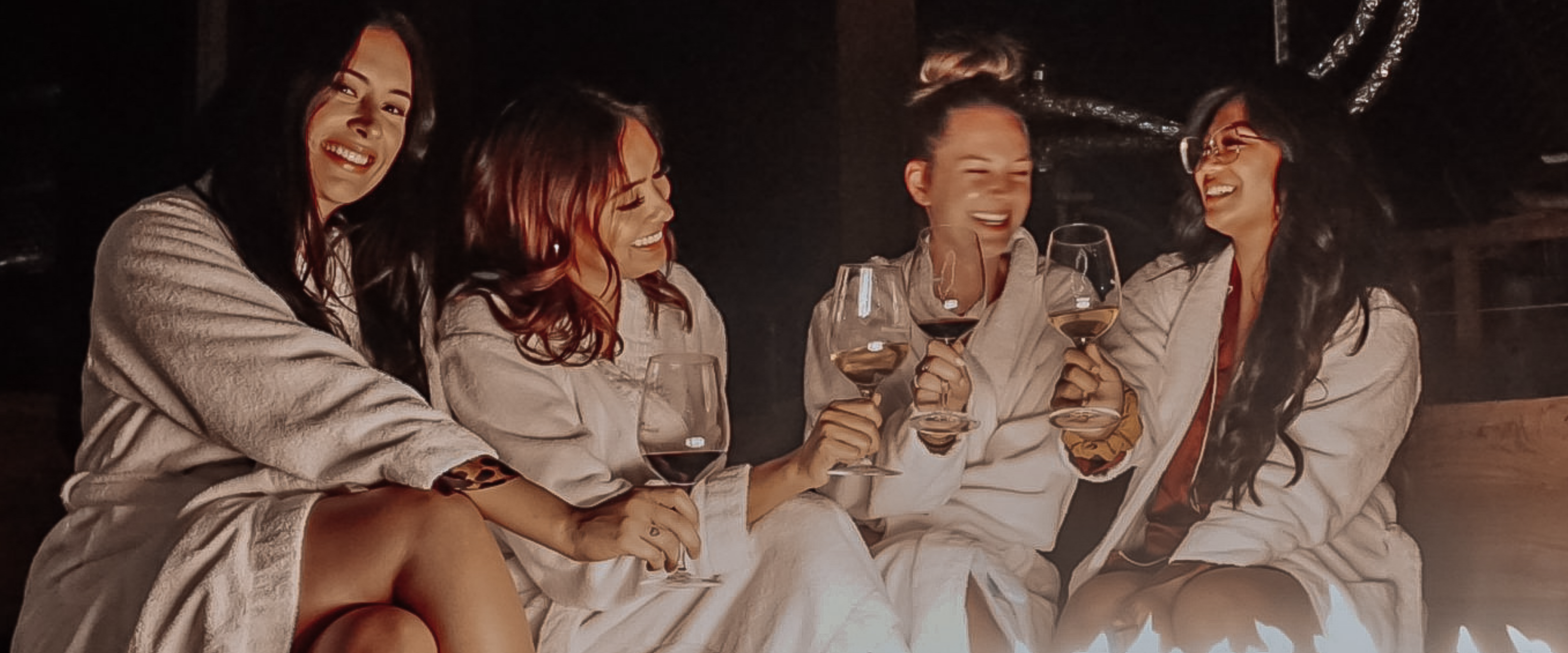 Group of four girls drinking wine by the fire