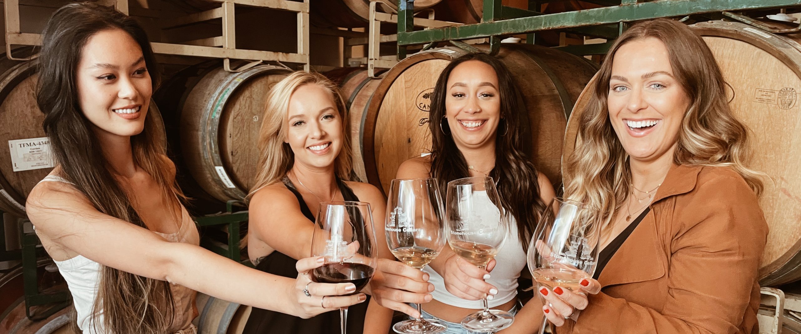 Four women drinking wine in the barrel room